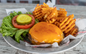 photo of a burger with it's bun off with lettuce and fries
