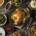 A thanksgiving table with turkey, fixings, sides, and dinnerware.