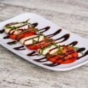 A caprese salad on a white plate.